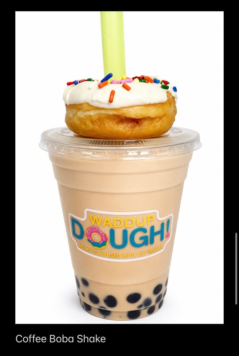 Waddup Dough! coffee boba shake topped with a frosted donut and sprinkles, with a green straw.