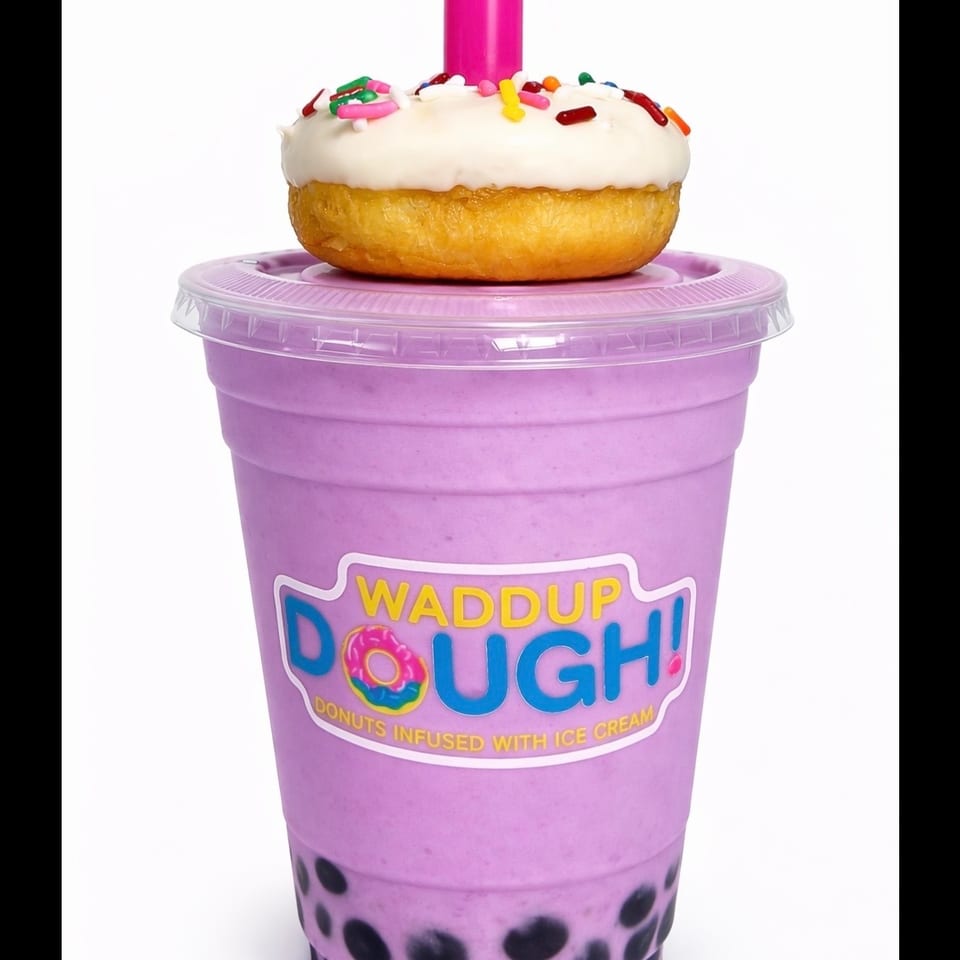 Taro boba shake with a white-frosted, sprinkle-covered donut on top, and a pink straw.